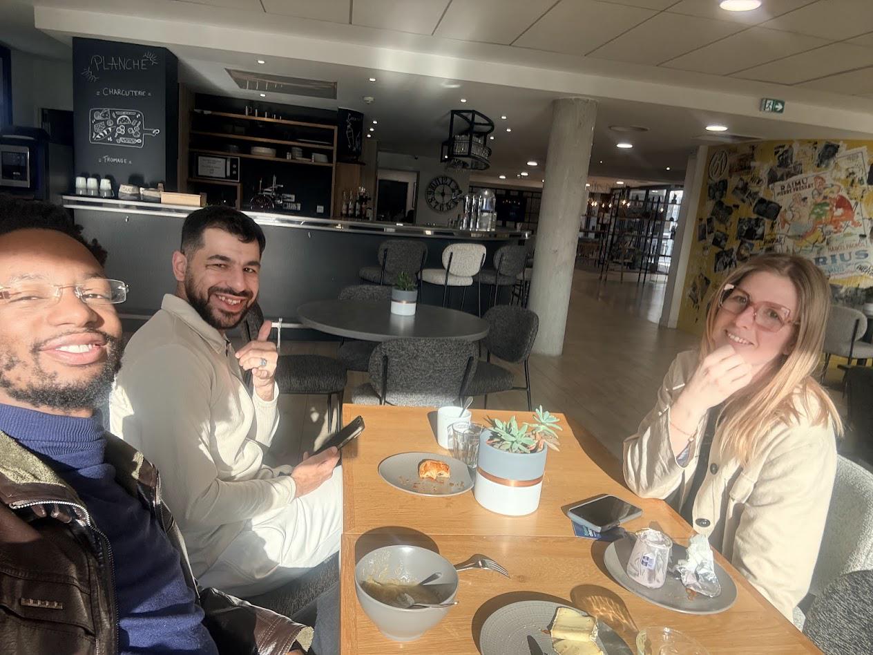 Photo de la Team Reborn : trois membres attablés autour d’un café dans un espace lounge
