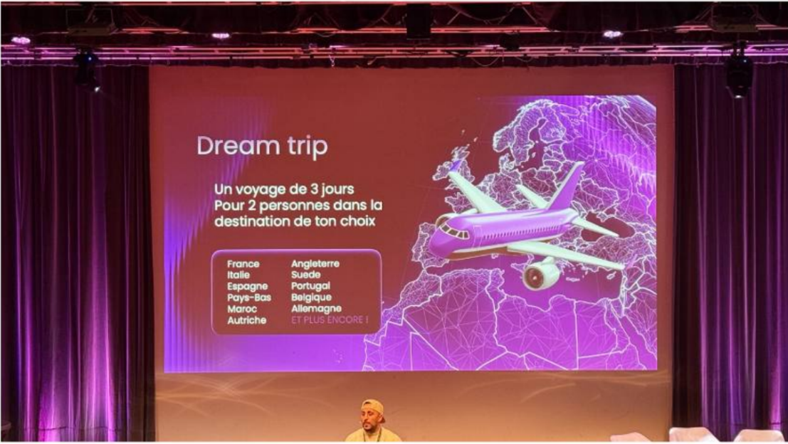 Sur la scène d’une convention, une diapositive « Dream trip » annonce un voyage de trois jours pour deux personnes vers la destination de son choix, parmi une douzaine de pays