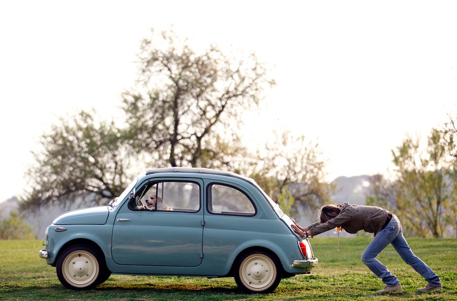 Photo d’illustration : une personne pousse une petite voiture à l’arrêt dans un pré, métaphore de l’effort initial des institutions pour lancer un mouvement avant de réduire leur engagement